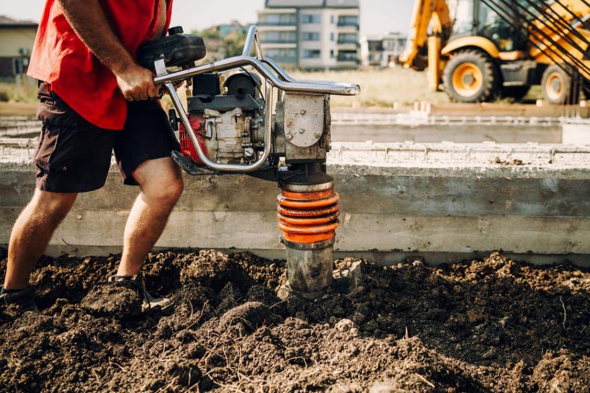 1 ouvrier du BTP manipule un mini-compacteur sur un chantier qui provoque des vibrations et entraine de la pénibilité