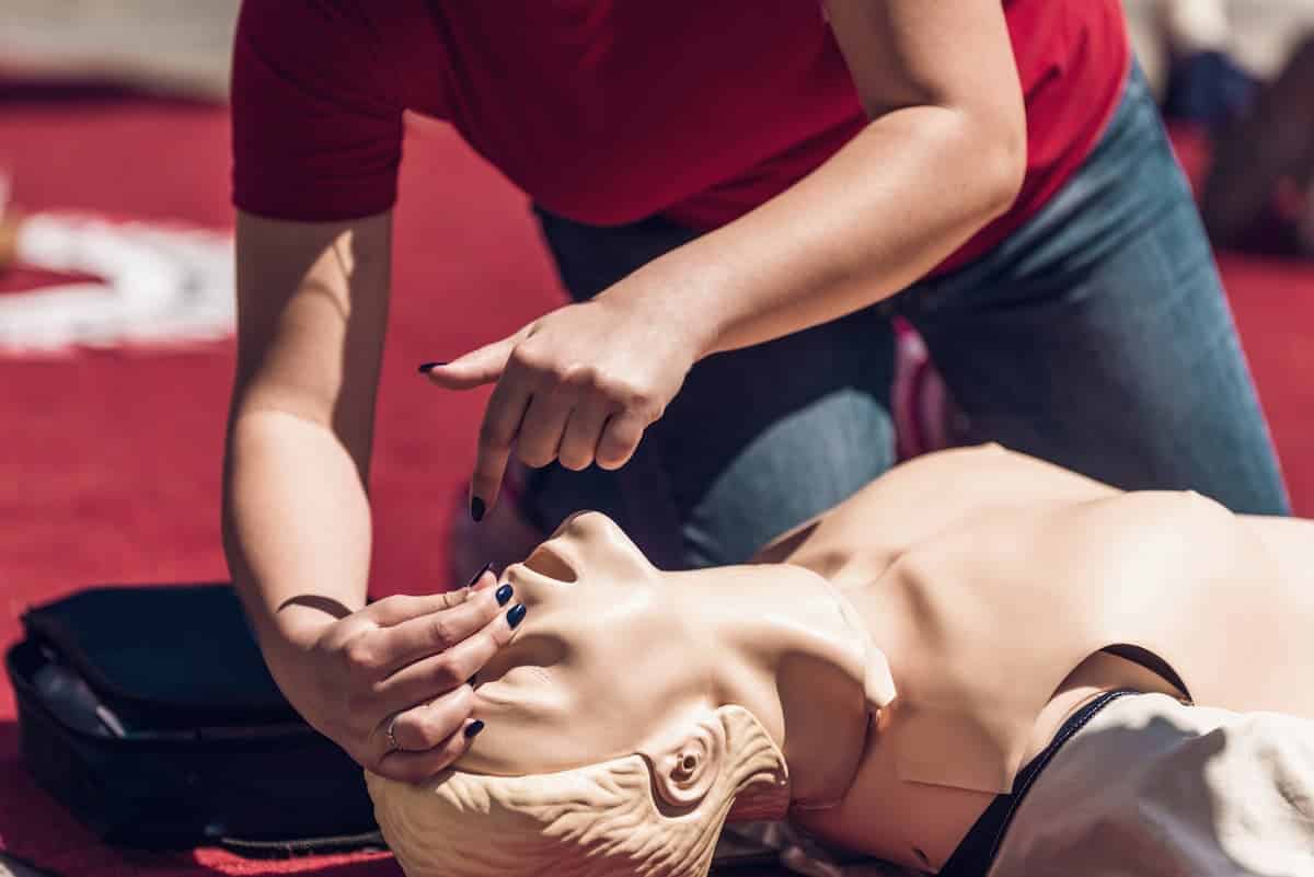 Une formatrice de secourisme explique la méthode du bouche à bouche sur un mannequin