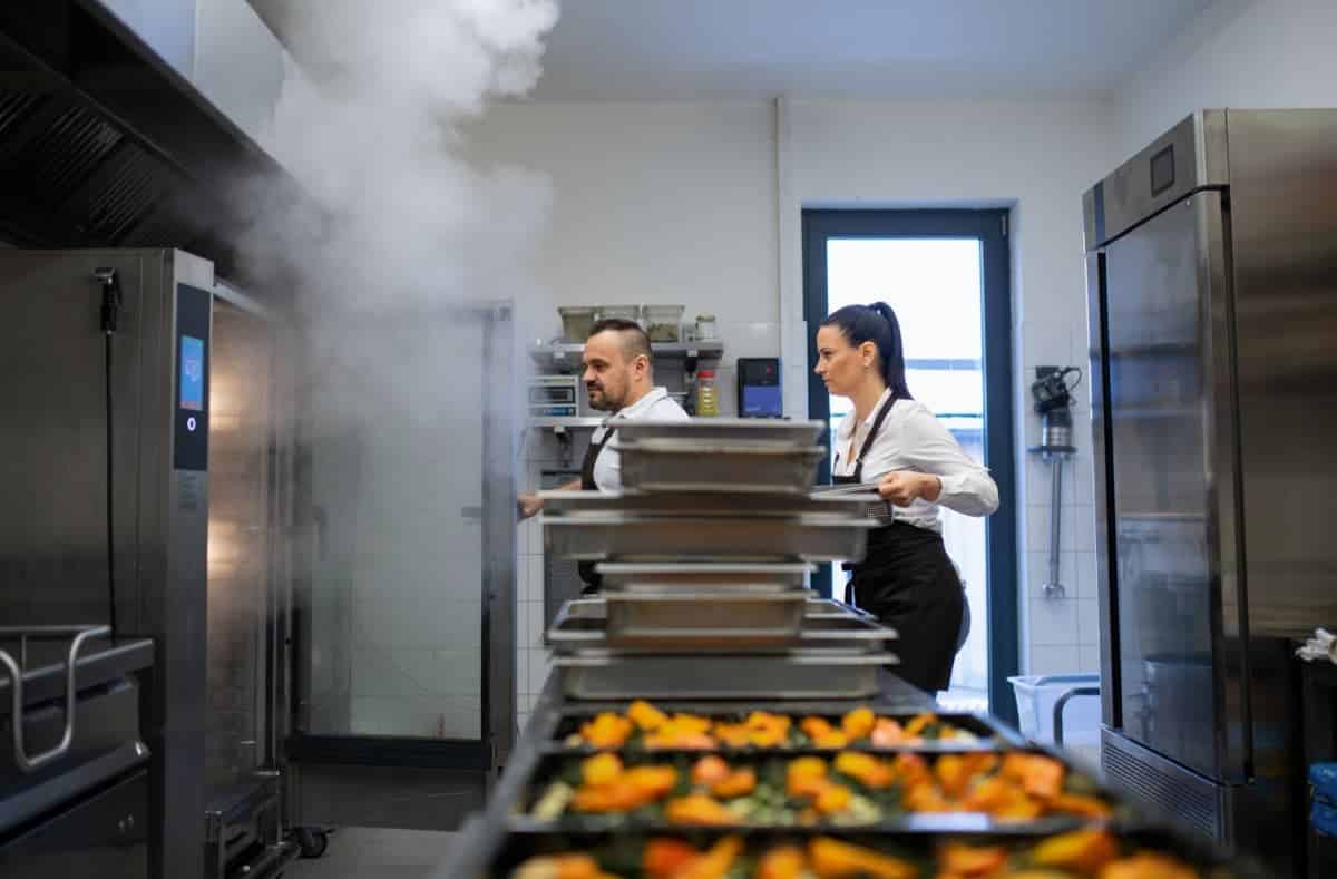 Une femme et un homme travaillent dans une cuisine dans laquelle les risques doivent être analysés en CST