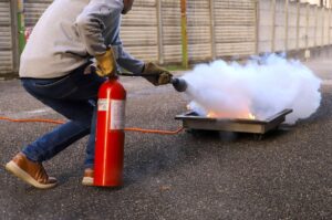 Un opérateur éteint un départ de feu avec un extincteur lors d'une formation sur bac à feu