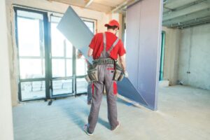 2 hommes portent une plaque de placo BA13 pour limiter les risques liés de TMS lors des gestes et postures
