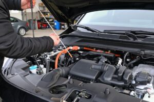 Gros plan sur un contrôle de niveau d'huile d'un véhicule hybride, une opération pour laquelle il faut être habilité B0L par l'employeur