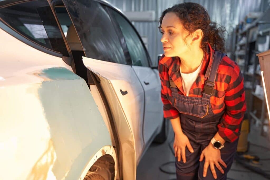 Une femme contrôle la carrosserie d'un véhicule électrique avec une habilitation B0L de la NF C18-550